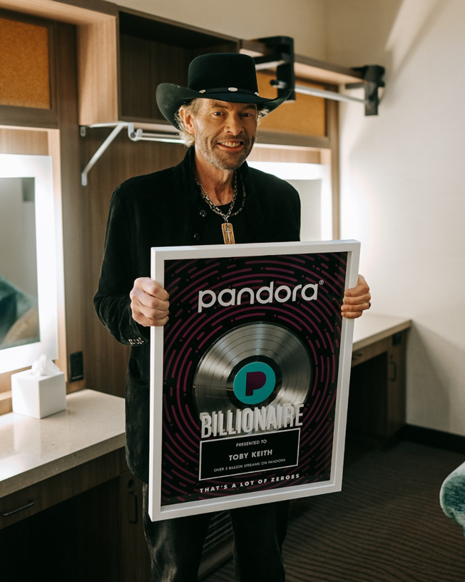 Toby Keith holding a Pandora Billionaire plaque